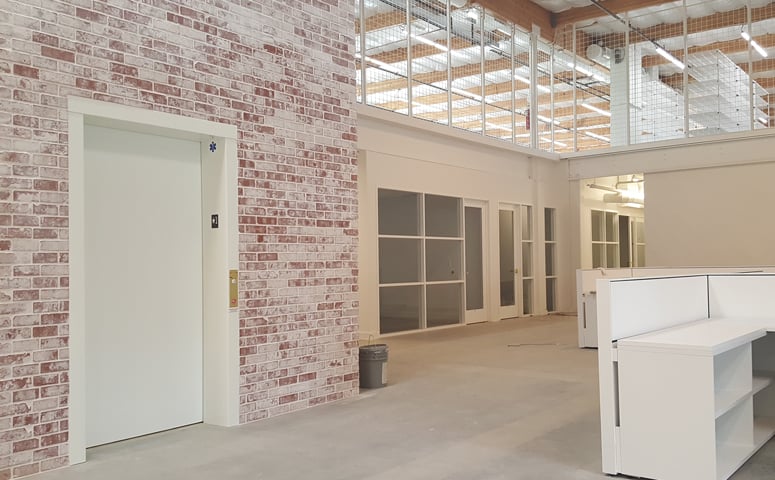 FashionPhile's reception area in their new Carlsbad headquarters with brick, white cage and sealed concrete.