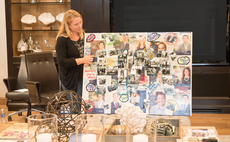 Hope Fox presents the core values collage she created using Hughes Marino ads and photos, complete with the initials “HM” spelled out in rope lights.
